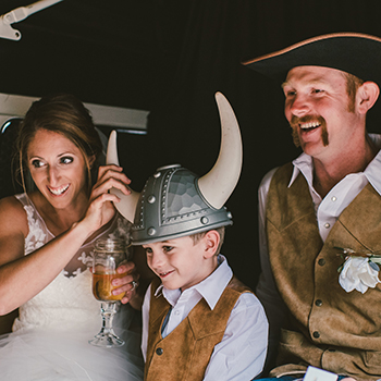 Bride and groom and page boy wearing props inside the Kombi taking a photo